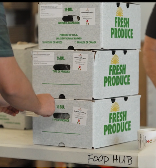 A stack of fresh produce boxes full of products for participants in the program