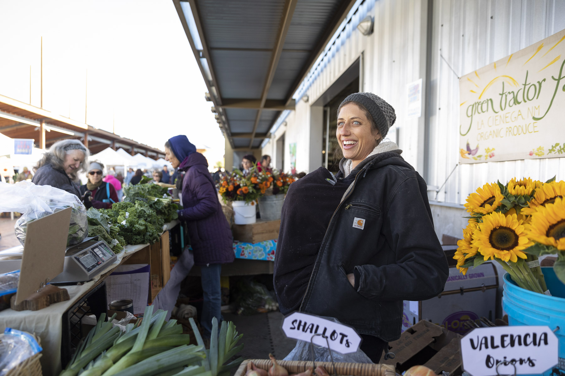 A vendor selling produce smiles outside the Santa Fe Farmers' Market